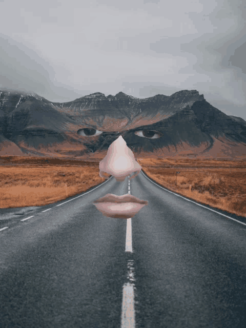 a road with mountains in the background and a face in the middle of the road