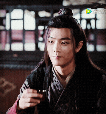a young man with long hair is holding a cup of tea