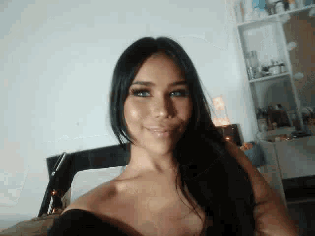 a woman is taking a selfie in a bedroom while sitting on a bed .