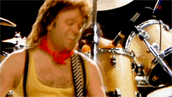 a man in a yellow tank top playing drums