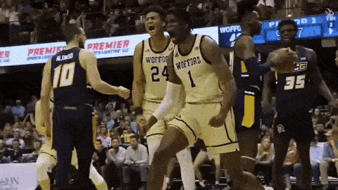 a group of basketball players are celebrating a win on a court .