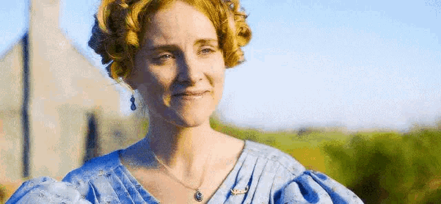 a woman is wearing a blue dress and a necklace .