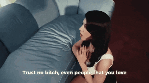 a woman is sitting on a couch with the words trust no bitch even people that you love