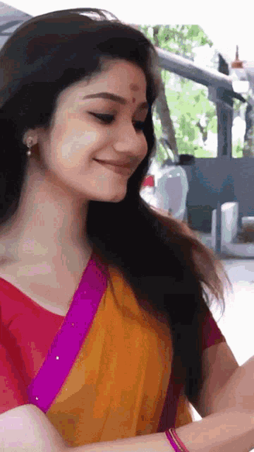 a woman in a yellow and pink saree smiles for the camera