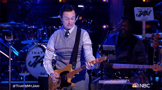 a man is playing a guitar in front of a drum that says that 's my jam