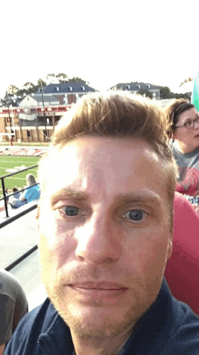 a man taking a selfie in front of a stadium that says ' liberty ' on the side