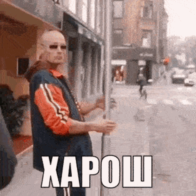 a man is standing on the side of a street holding a sign that says ' xapo ' on it .