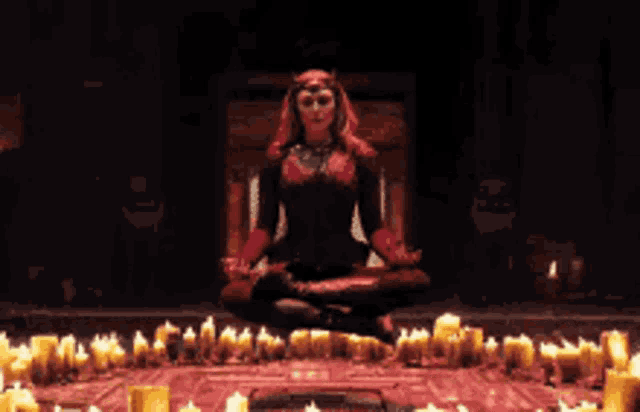 a woman in a costume is sitting in a lotus position in front of a circle of candles .