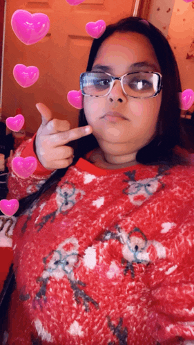 a woman wearing glasses and a red sweater giving a thumbs up