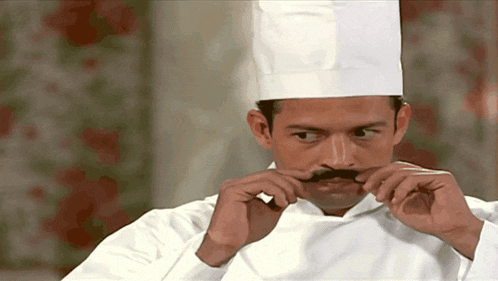 a man in a chef 's uniform has a fake mustache on his face