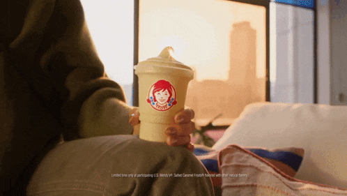 a person is holding a wendy 's cup in their lap