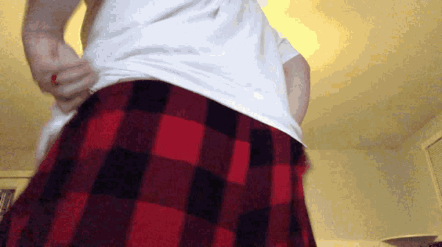 a man wearing a white shirt and red and black plaid pants