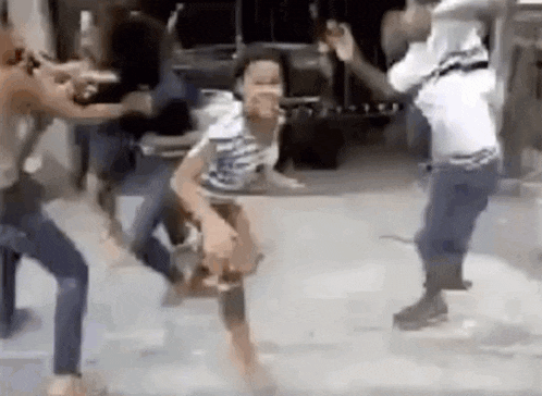 a group of people are fighting on a street .