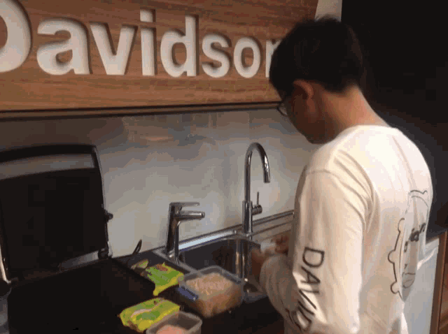 a man in a davidson shirt washing dishes