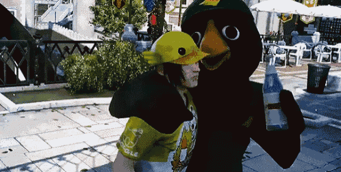 a man in a duck costume holds a bottle of water in his hand