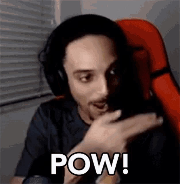 a man wearing headphones is sitting in an orange chair and making a funny face .
