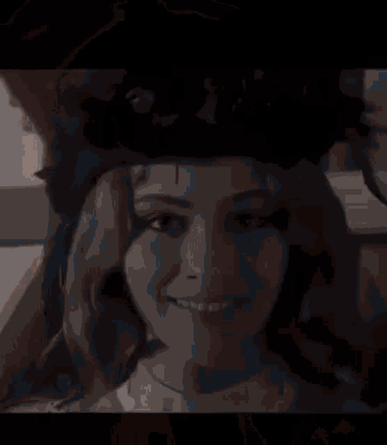 a woman is sitting at a table in front of a mirror drinking from a glass .