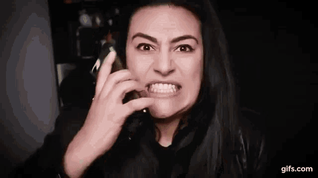 a woman is making a funny face while talking on her cell phone .