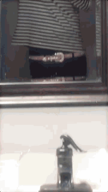 a person 's reflection in a mirror with a striped shirt on