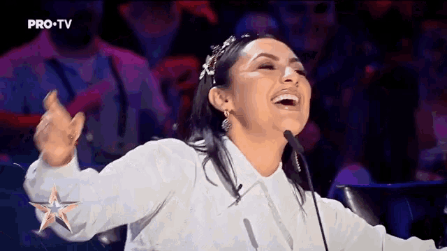a woman is laughing while sitting in front of a microphone with pro-tv written on the bottom