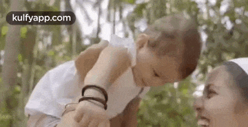 a woman is holding a baby in her arms and looking at it .