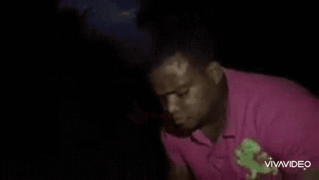 a man in a pink shirt is making a funny face in a video .