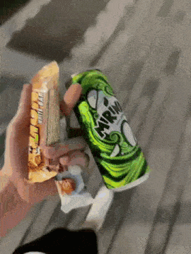 a person holding a can of mirinda next to a bag of chips