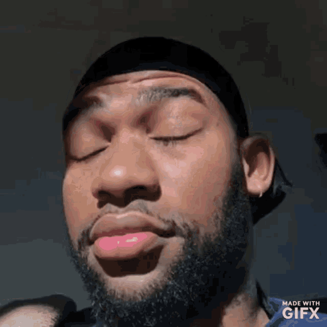 a man with a beard and a bandana on his head is making a funny face .