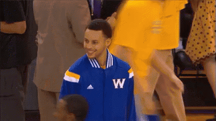a basketball player wearing a blue jacket with the letter w on it is smiling while standing on a court .