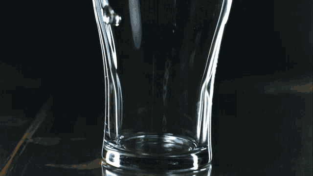 a glass of liquid is being poured into it with ice
