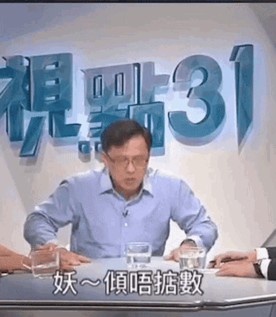 a man sits at a table in front of a wall that has the number 31 on it