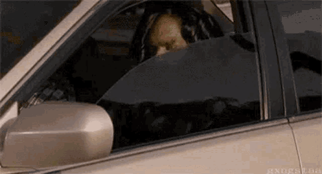 a man is sitting in the driver 's seat of a car looking out the window .