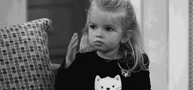 a little girl is sitting on a couch with a pillow in her hand .