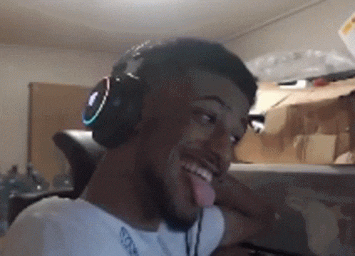 a man wearing headphones is sticking his tongue out while sitting at a desk .