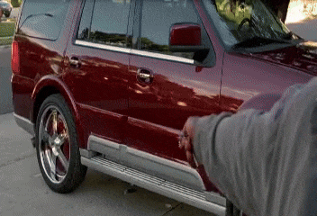 a man is opening the door of a red suv in a driveway .
