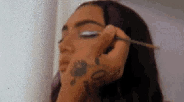 a woman is getting her makeup done by a makeup artist .