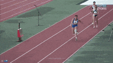 a woman running on a track with the number 100 on her top