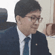 a man in a suit and tie is sitting at a desk with glasses .