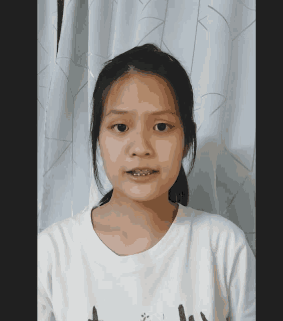 a girl with braces on her teeth wears a white shirt