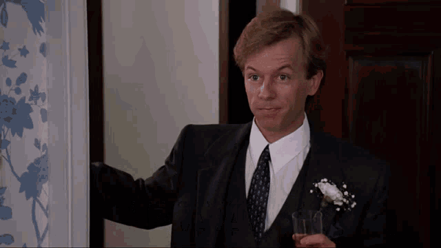 a man in a suit and tie holds a glass in his hand