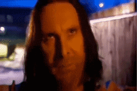a man with long hair looks at the camera in a pixelated image