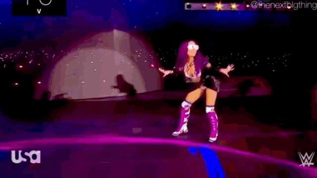 a woman is dancing on a stage with a tent in the background and a wrestling logo in the corner .