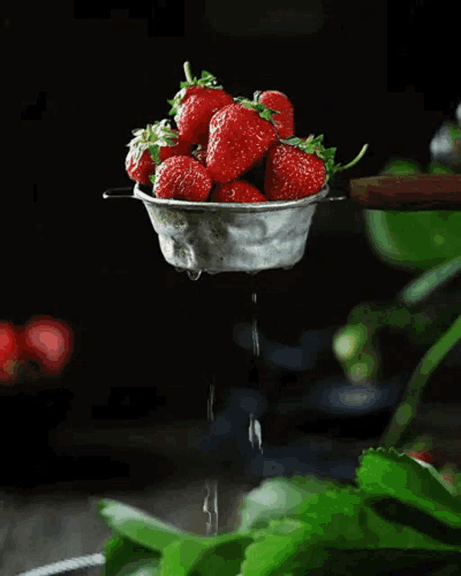 strawberries are being squeezed through a strainer with water dripping out of it