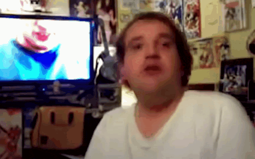 a man in a white shirt is sitting in front of a tv