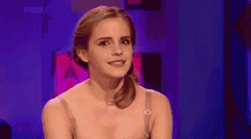 a woman in a bra is sitting in front of a purple background and smiling .