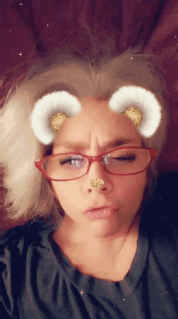 a woman wearing glasses and a nose ring making a funny face