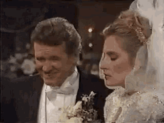 a man and a woman are standing next to each other at a wedding .