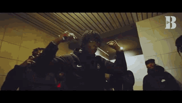 a group of people are standing in a room with their hands in the air .