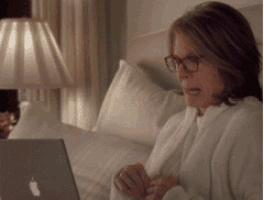 a woman wearing glasses is sitting in bed using an apple laptop