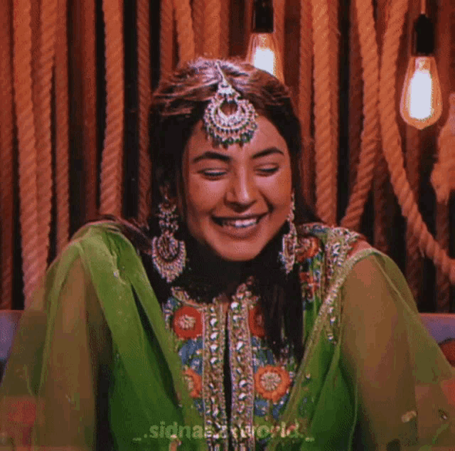 a woman wearing a green dress and earrings smiles